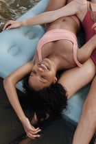 A woman with brunette hair looking up with pouty lips and a strand of hair between her lips and nose