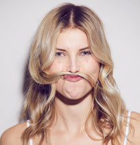 A woman posing with her long hair as a fake moustache