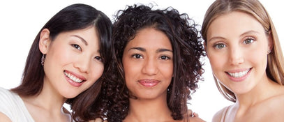 Three women of different ethnicities smiling facing the camera