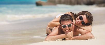 A man and woman lying on a beach near the water's edge
